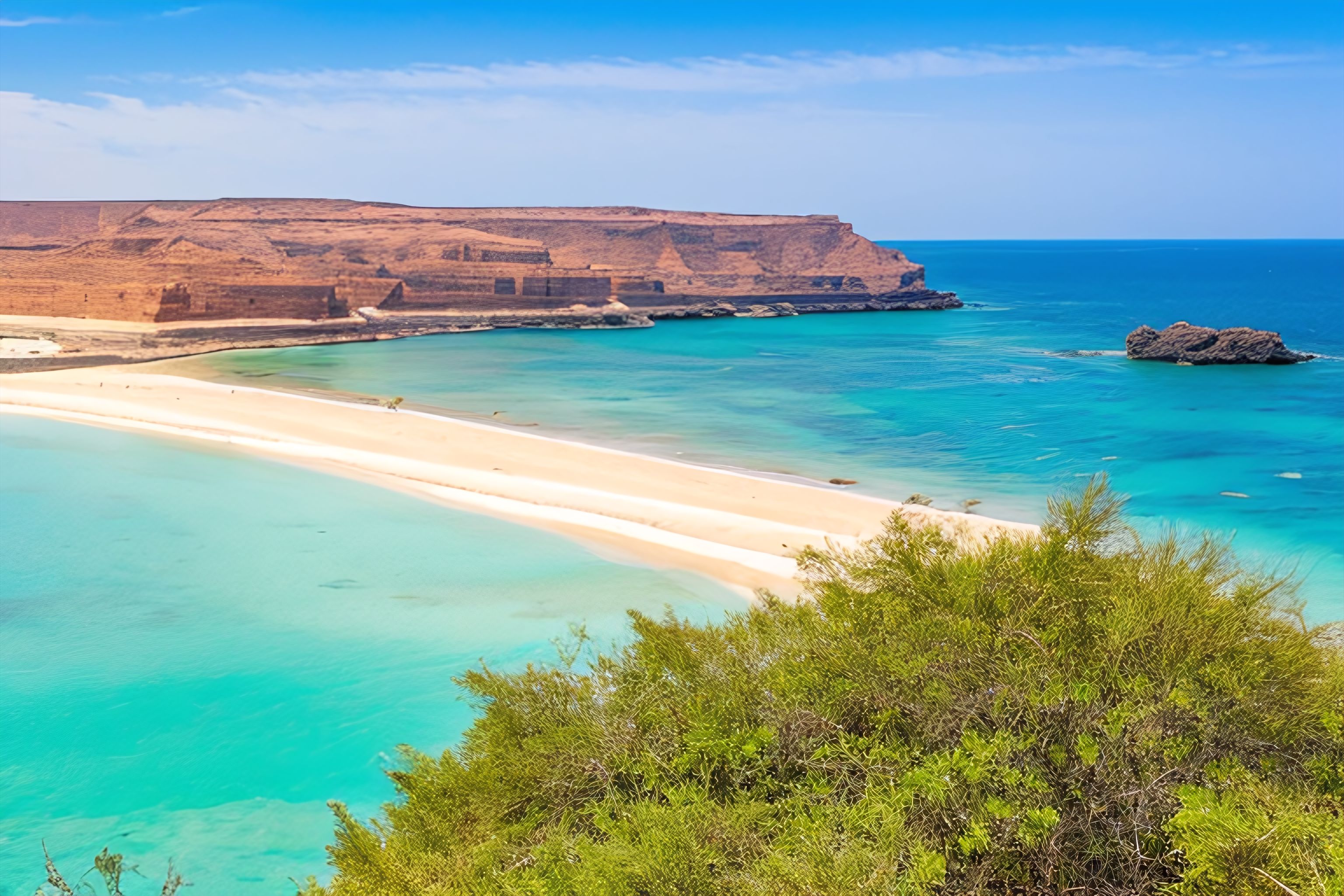 A panoramic view of a beach in Djibouti, with crystal-clear waters and rocky cliffs in the distance.
