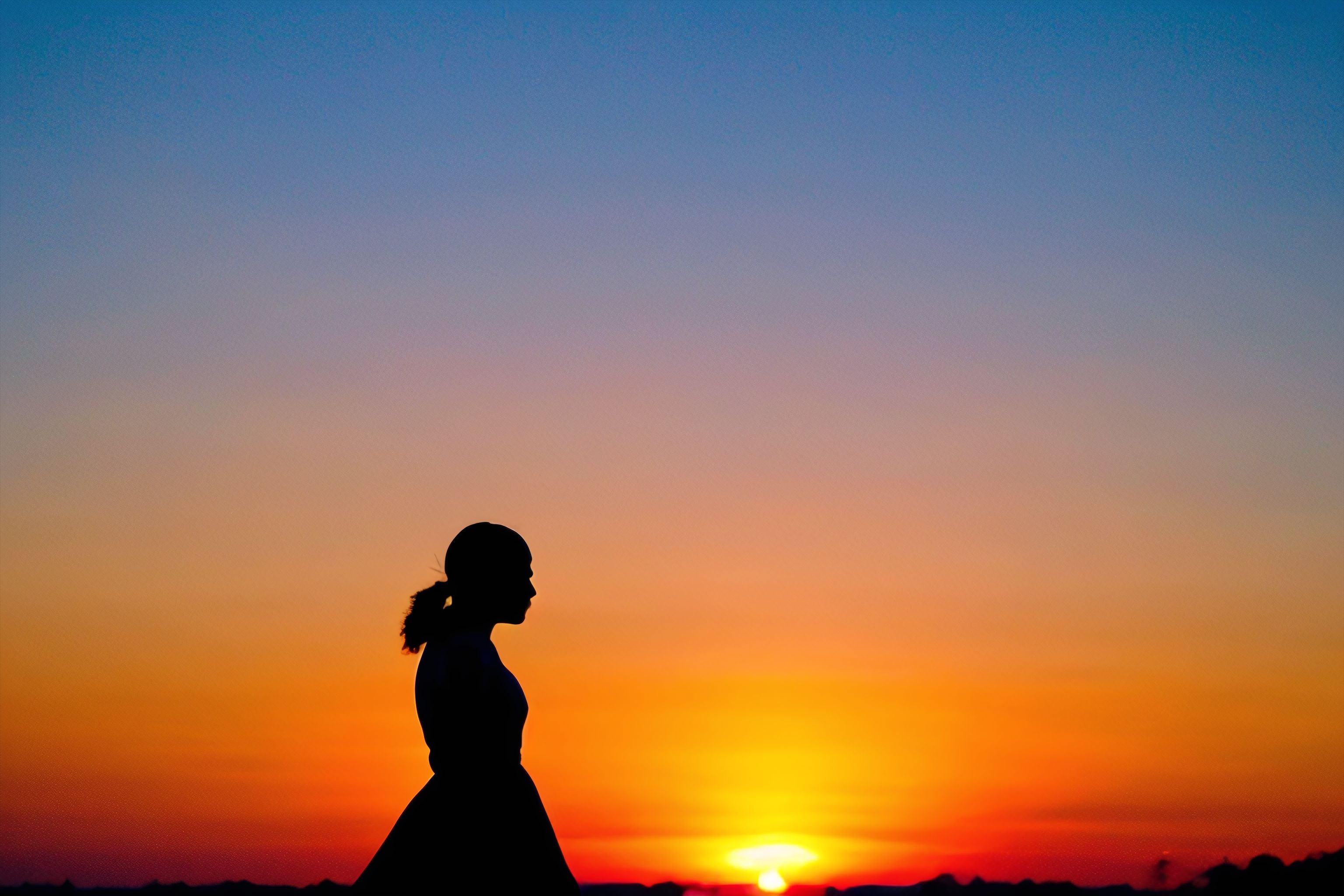 A silhouette of a figure skater against a colorful sunset sky.