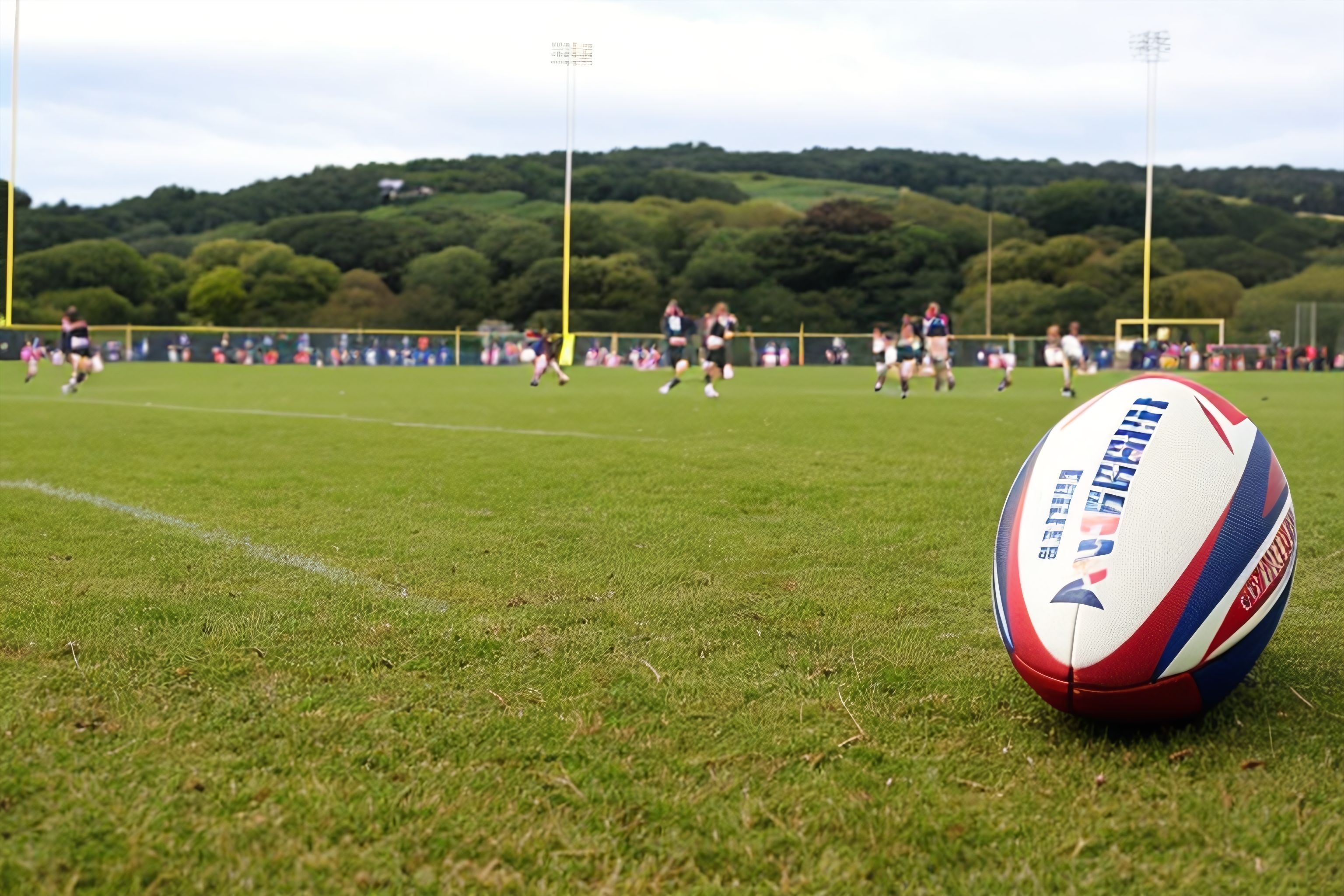 A rugby ball on a grassy field with players in the background